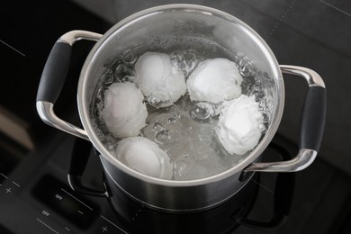 Chicken eggs boiling in pot on electric stove, above view