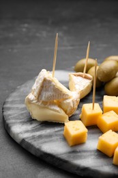 Photo of Toothpick appetizers. Different cheese on black table