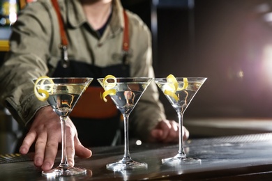 Photo of Barman serving glasses of lemon drop martini on counter, closeup. Space for text