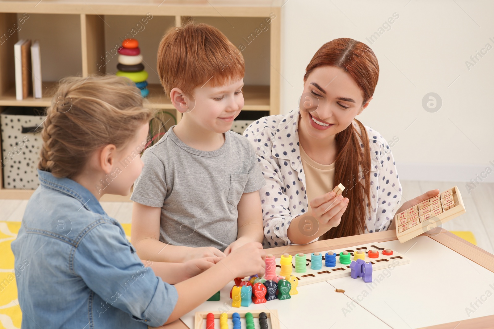 Photo of Happy mother and children playing with different math game kits at desk in room. Study mathematics with pleasure