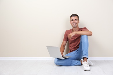 Man in casual clothes with laptop near color wall