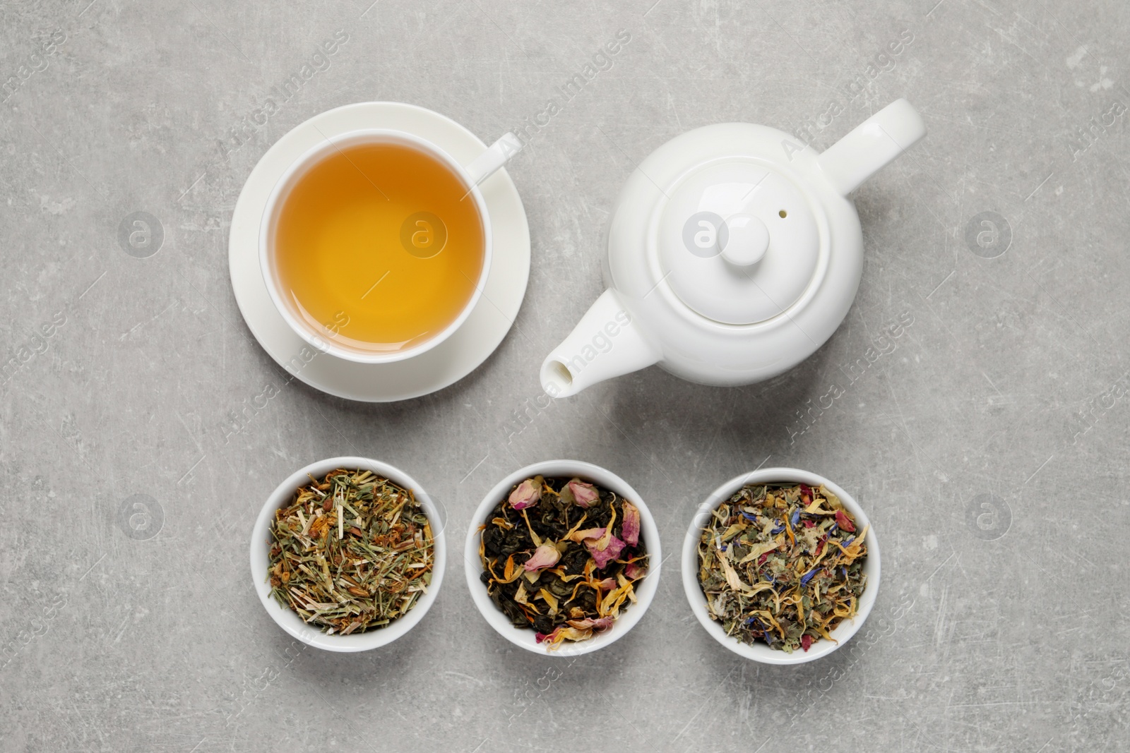 Photo of Fresh brewed tea and dry leaves on light grey background, flat lay