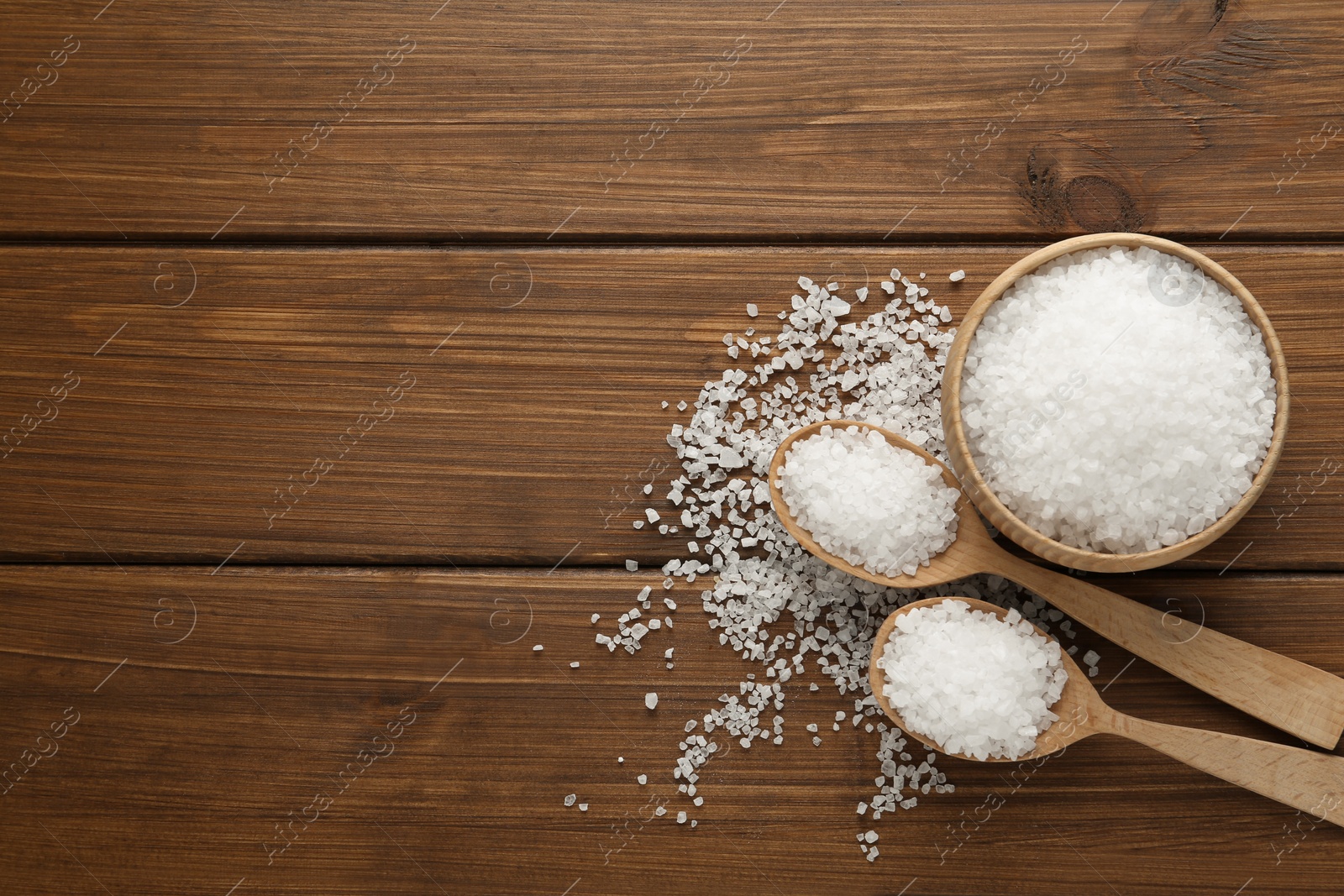 Photo of Natural sea salt on wooden table, flat lay. Space for text