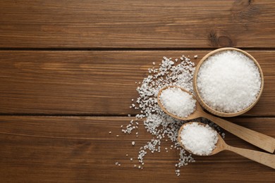 Natural sea salt on wooden table, flat lay. Space for text