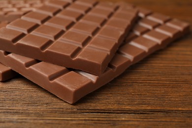 Photo of Tasty sweet chocolate bars on wooden table, closeup