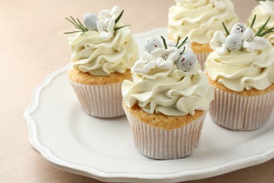 Tasty Easter cupcakes with vanilla cream on wooden table, closeup