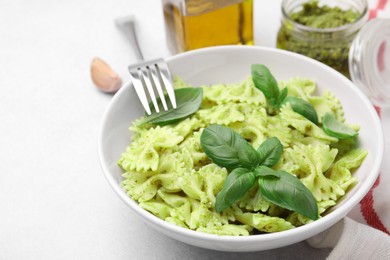 Photo of Delicious pasta with pesto sauce and basil served on light table, closeup. Space for text