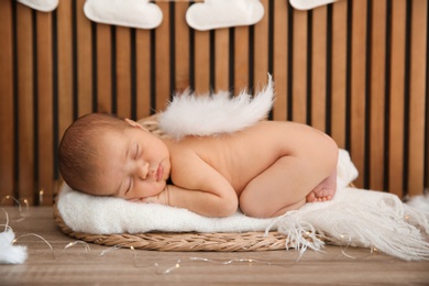 Cute newborn baby as Christmas angel in decorated studio