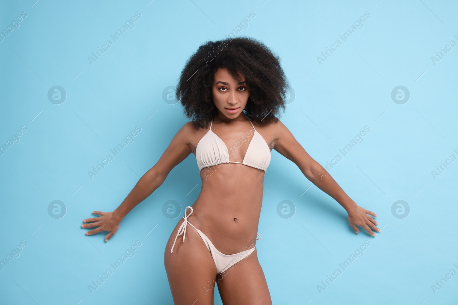 Photo of Beautiful woman in stylish bikini on light blue background