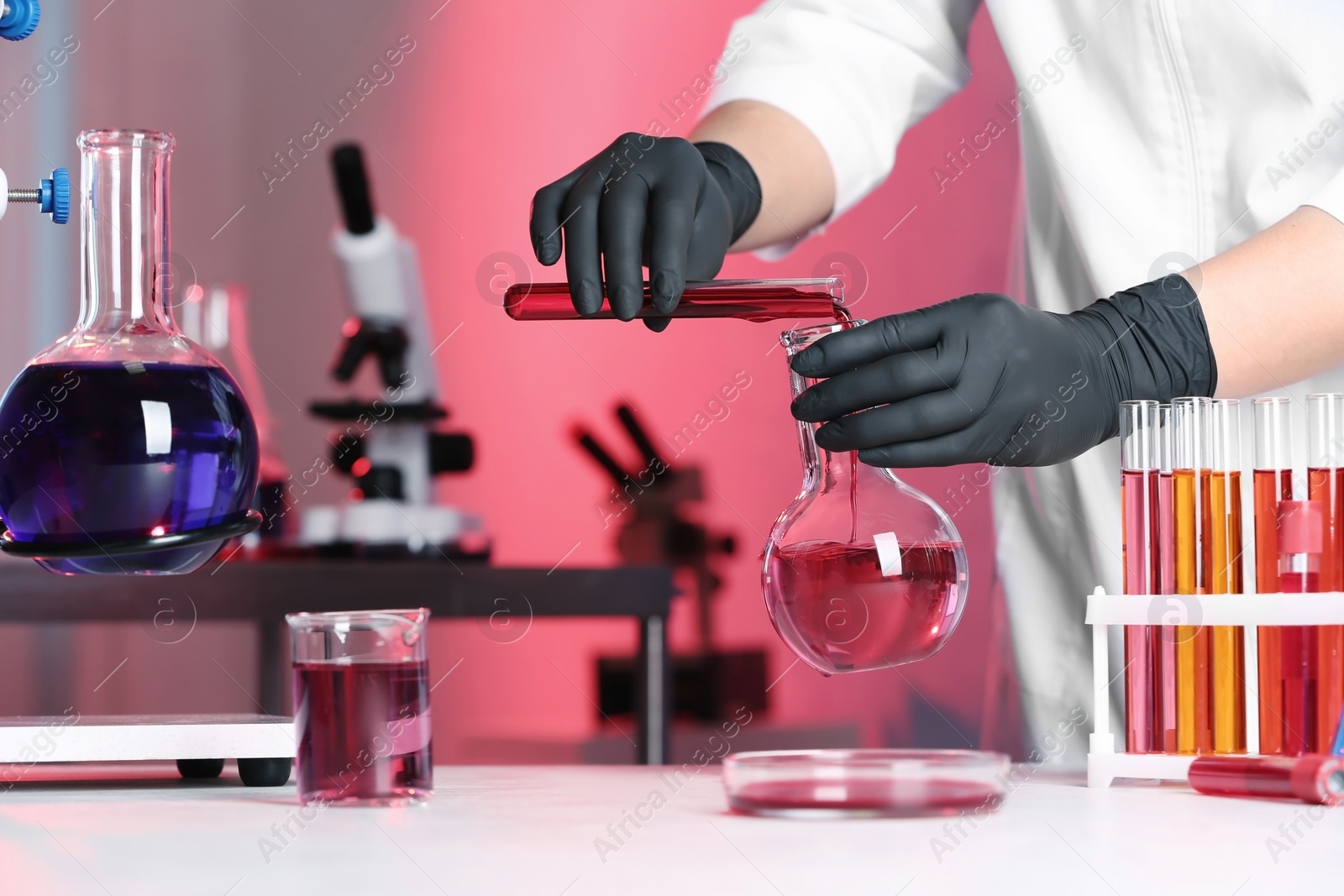 Photo of Scientist pouring reagent into flask at table in chemistry laboratory