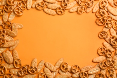 Photo of Frame of delicious crackers on orange background, flat lay. Space for text