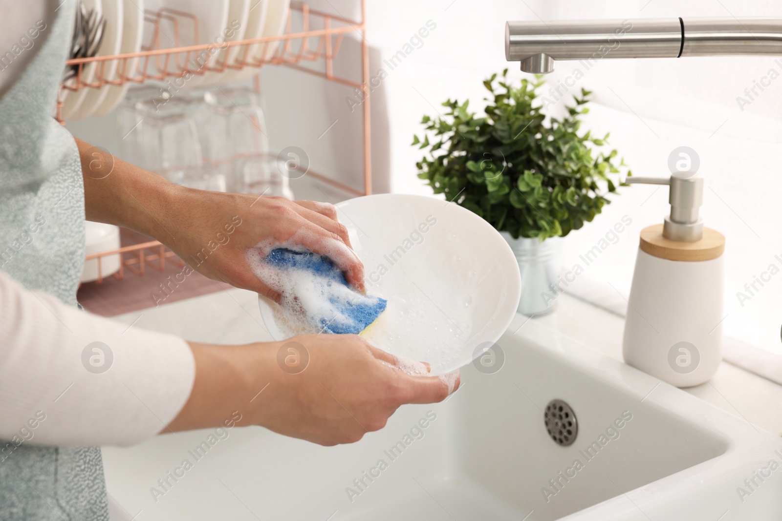 Photo of Woman washing bowl at sink in kitchen, closeup