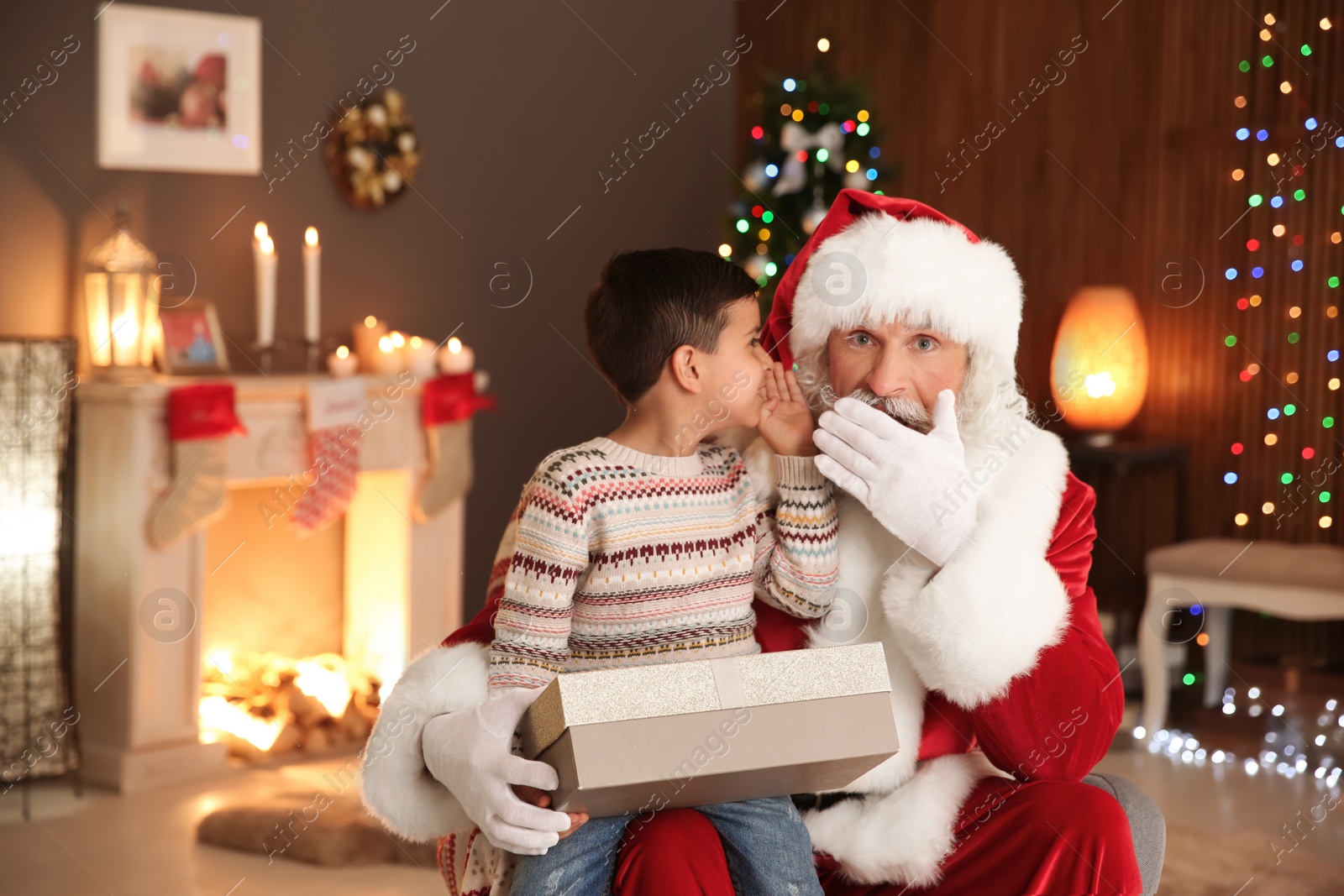 Photo of Little child with Santa Claus and Christmas gift at home