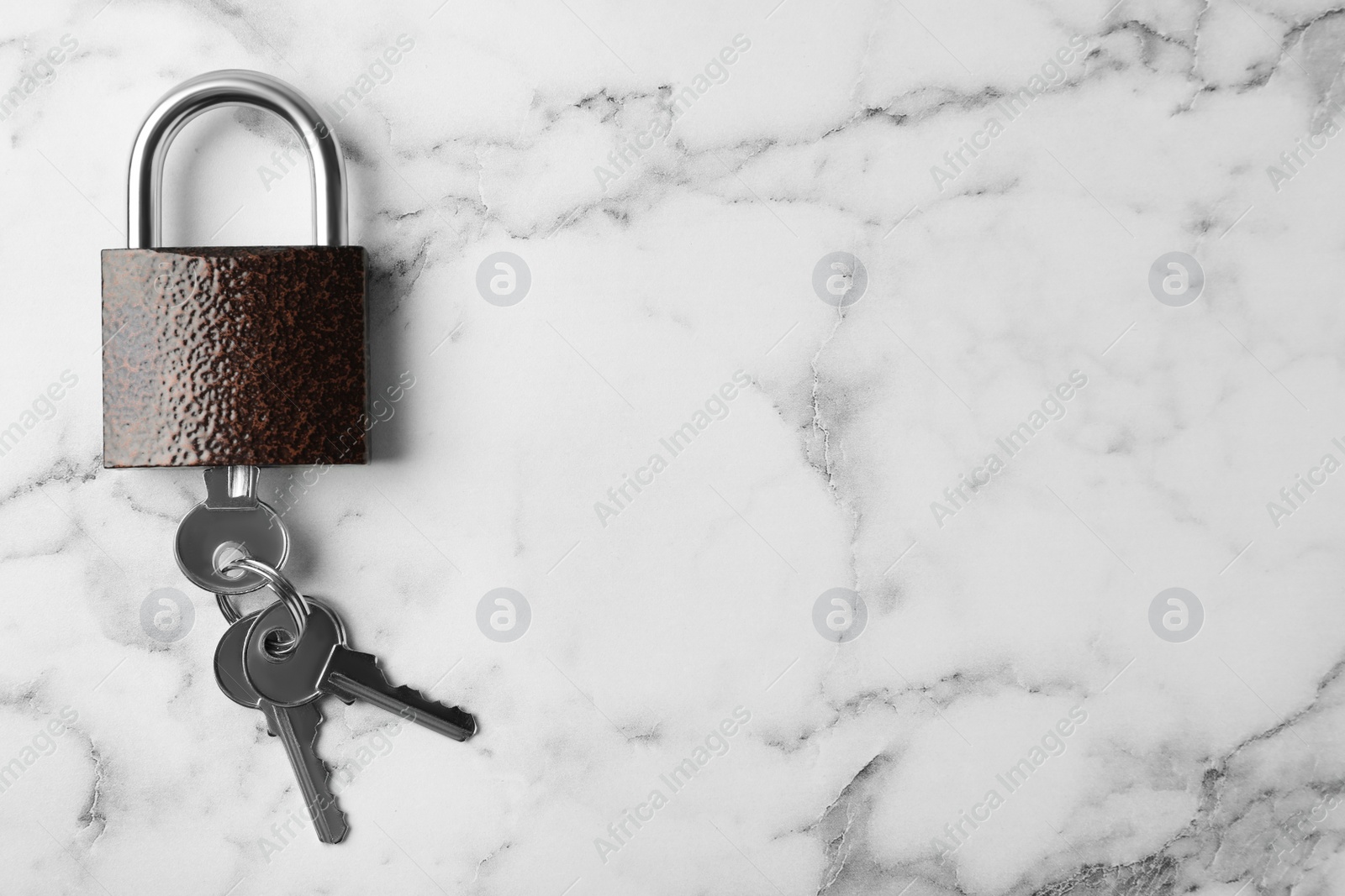 Photo of Steel padlock, keys and space for text on white marble background, top view. Safety concept