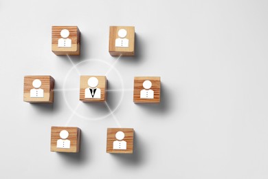 Team management. Wooden cubes with human icons linked together symbolizing company structure on white background table, top view. Space for text