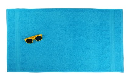 Photo of Clean light blue beach towel and sunglasses on white background, top view
