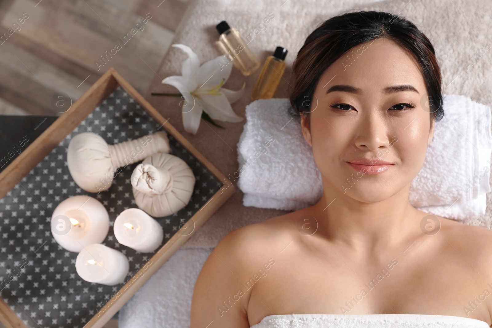 Photo of Beautiful Asian woman lying on massage table in salon, top view