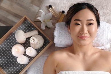 Beautiful Asian woman lying on massage table in salon, top view