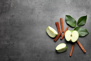 Photo of Fresh apple and cinnamon sticks on gray table, top view