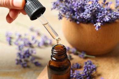 Woman dripping lavender essential oil into bottle, closeup