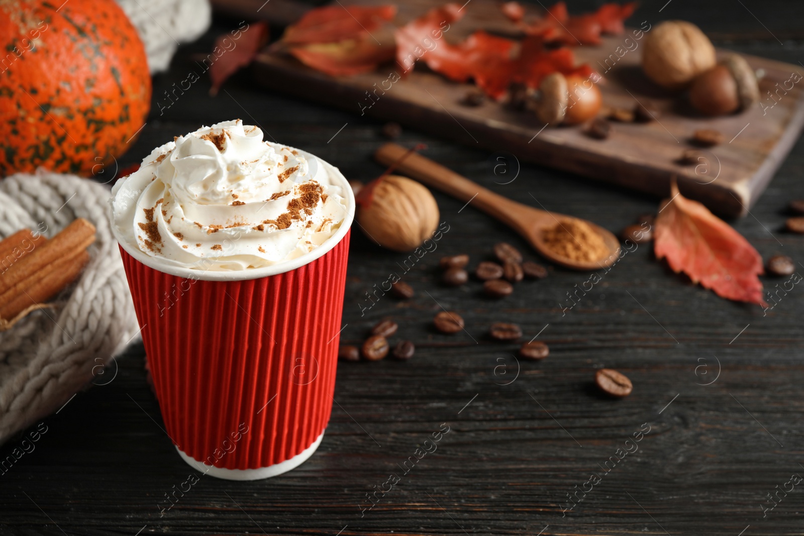 Photo of Paper cup with tasty pumpkin spice latte on black wooden table. Space for text