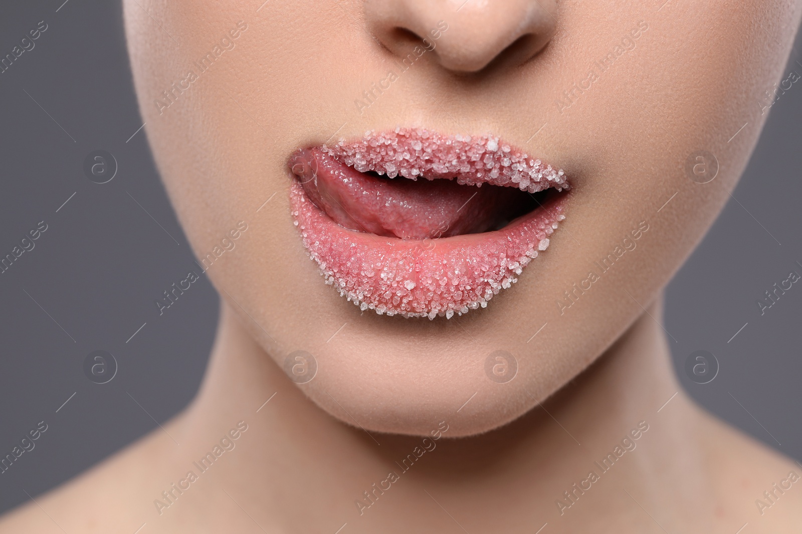 Photo of Woman with beautiful lips covered in sugar on grey background, closeup