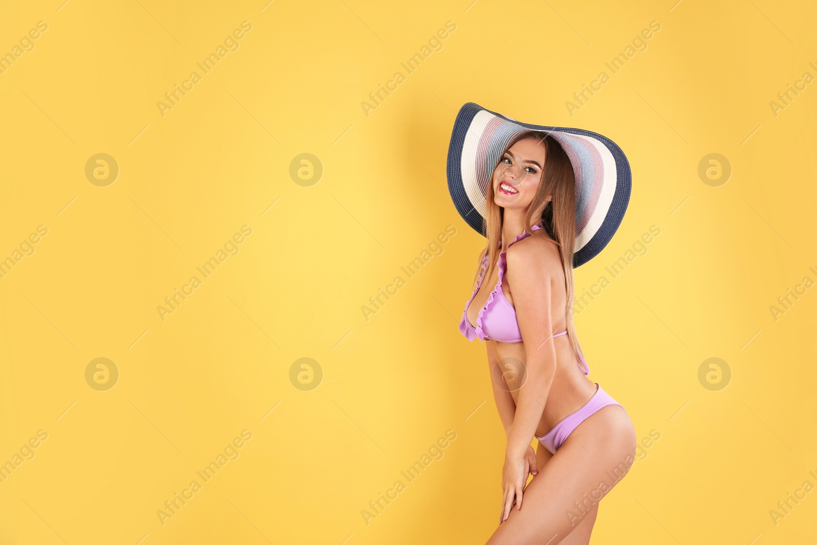 Photo of Pretty sexy woman in stylish bikini with hat on color background, space for text