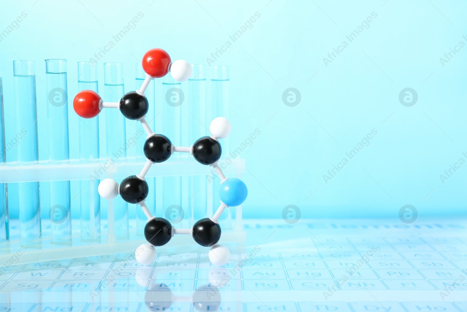 Photo of Molecular model and test tubes against light blue background, space for text