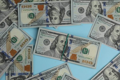 Photo of Money exchange. Dollar banknotes on light blue background, top view