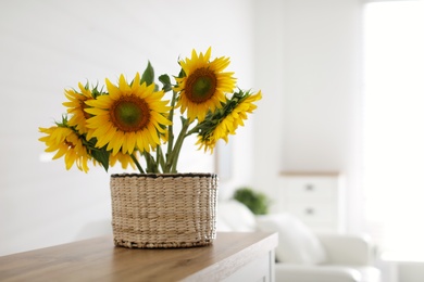 Photo of Beautiful yellow sunflowers on wooden table in room, space for text