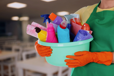 Image of Woman holding basin with cleaning supplies at school canteen, closeup
