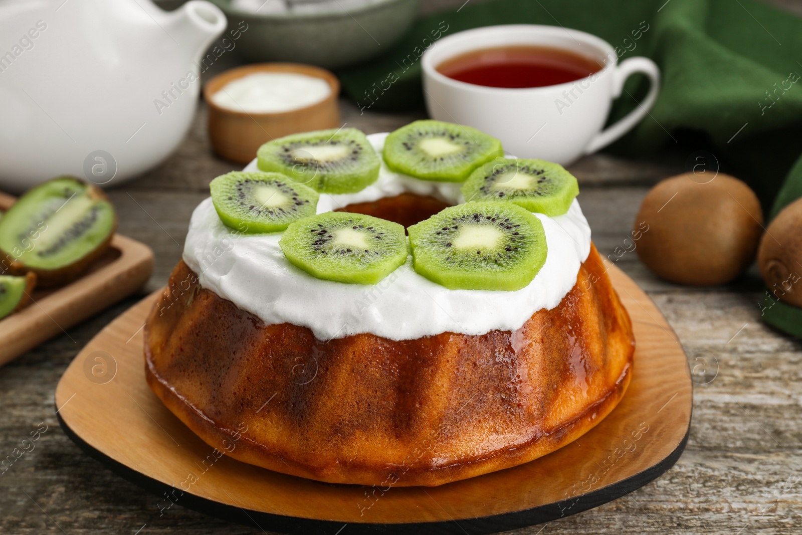 Photo of Homemade yogurt cake with kiwi and cream on wooden table