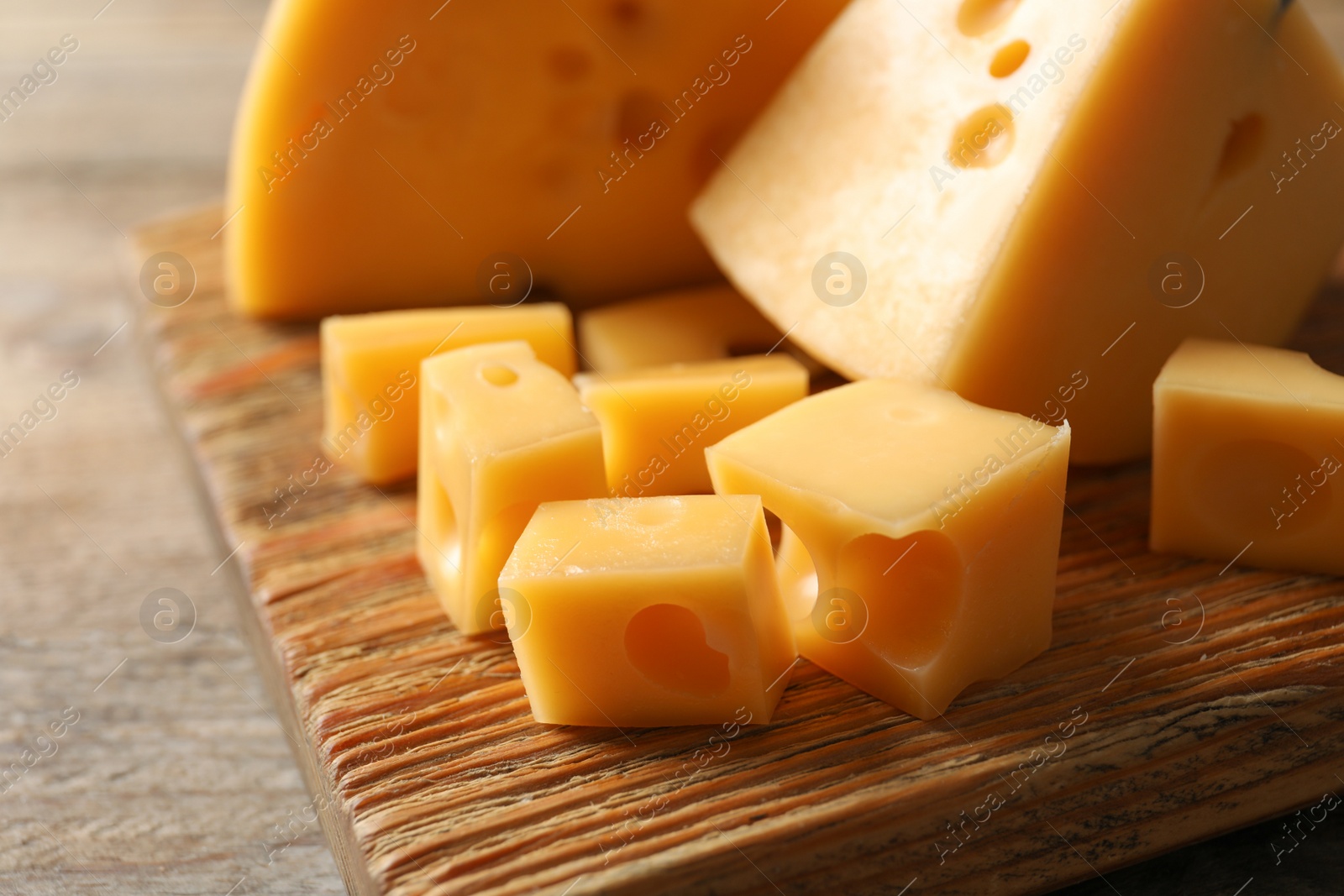 Photo of Serving board with delicious cheese on wooden table, closeup
