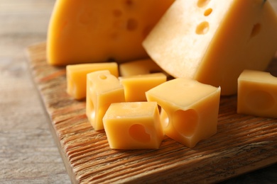 Serving board with delicious cheese on wooden table, closeup