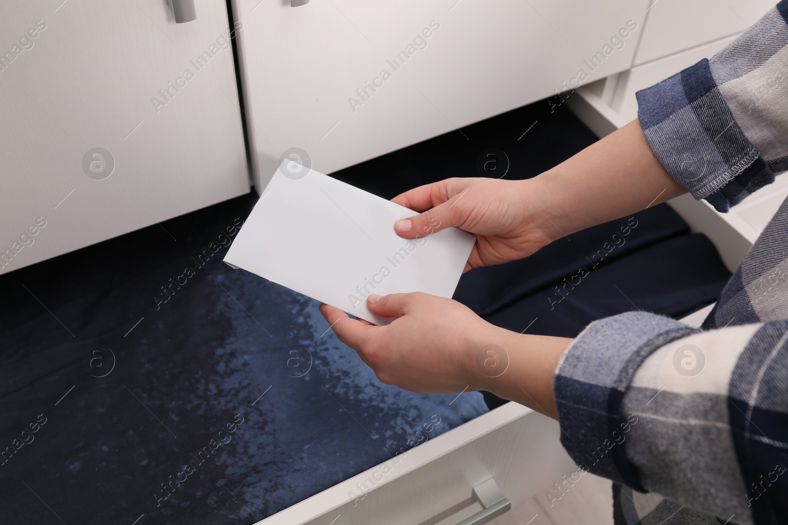 Photo of Woman putting scented sachet into drawer with linens, closeup