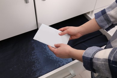 Woman putting scented sachet into drawer with linens, closeup