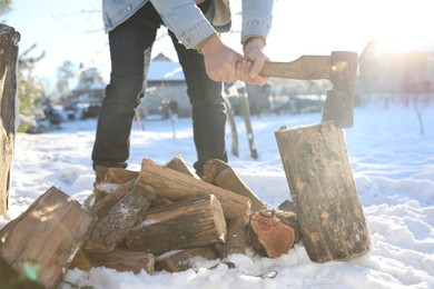 Photo of Man chopping wood with axe outdoors on winter day, closeup