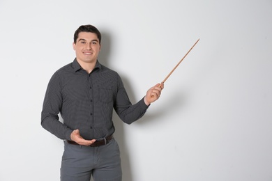 Portrait of male teacher with pointer on light background