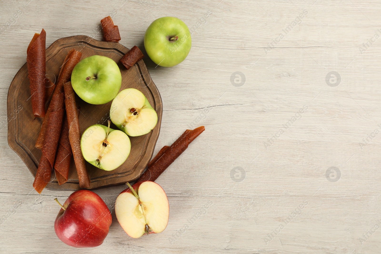 Photo of Flat lay composition with delicious fruit leather rolls on wooden table. Space for text