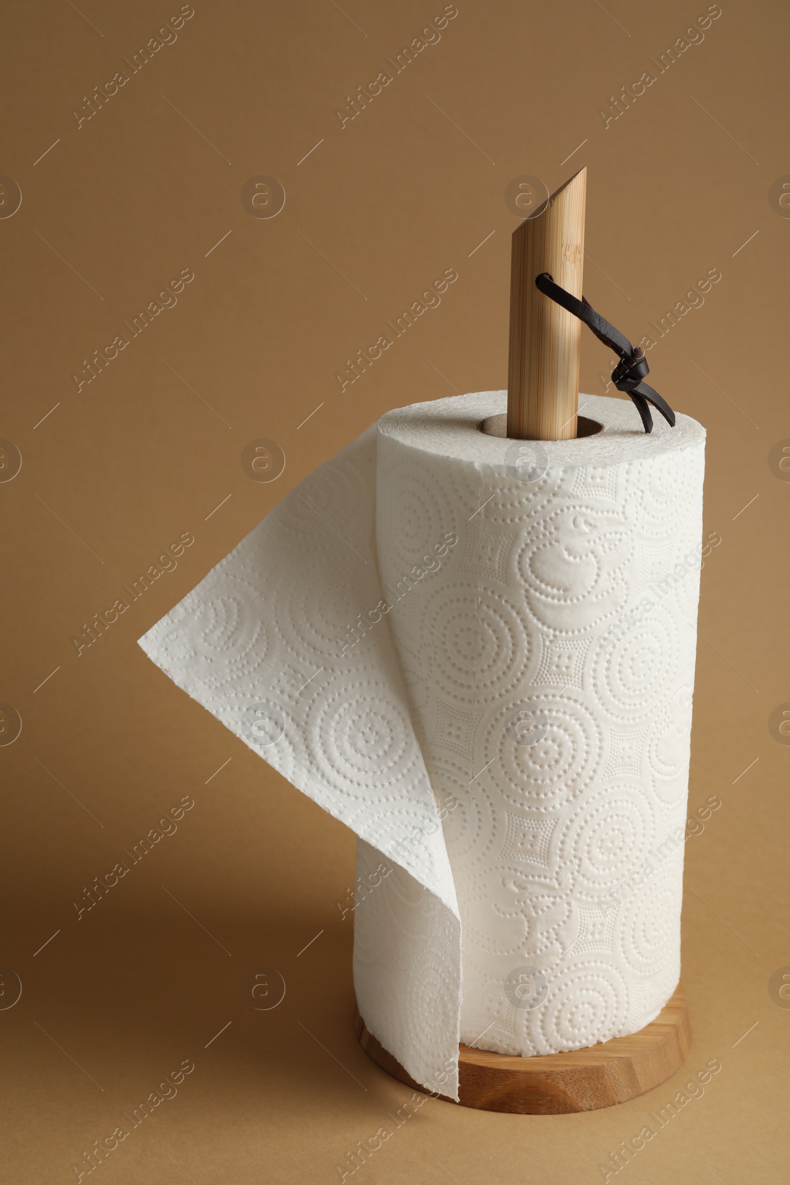 Photo of Holder with roll of white paper towels on brown background