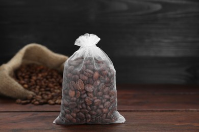 Photo of Scented sachet with coffee beans on wooden table, closeup