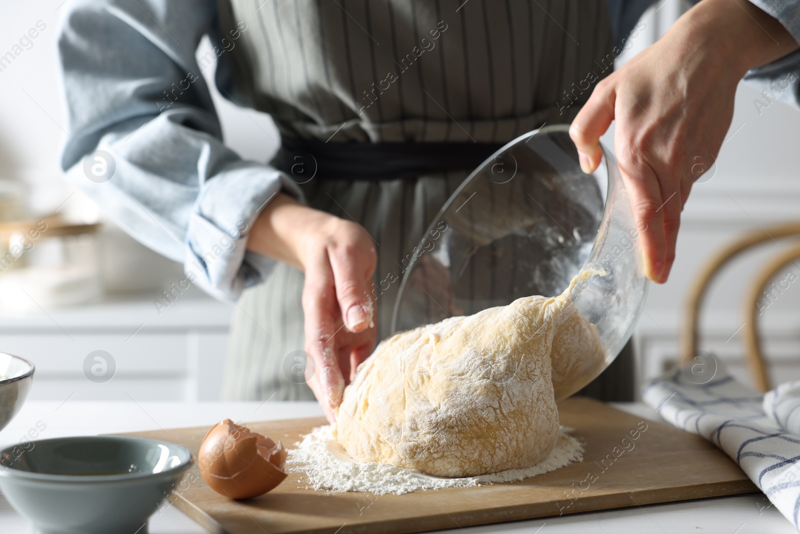 Photo of Woman kneading dough at white wooden table in kitchen, closeup