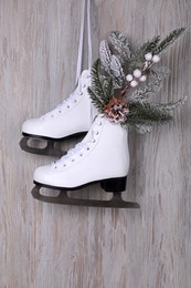 Photo of Pair of ice skates with Christmas decor hanging on wooden wall