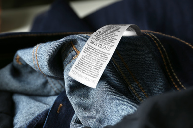 Photo of Clothing label with care instructions and content information on denim garment, closeup