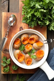 Photo of Delicious cooked snails served on wooden table, flat lay