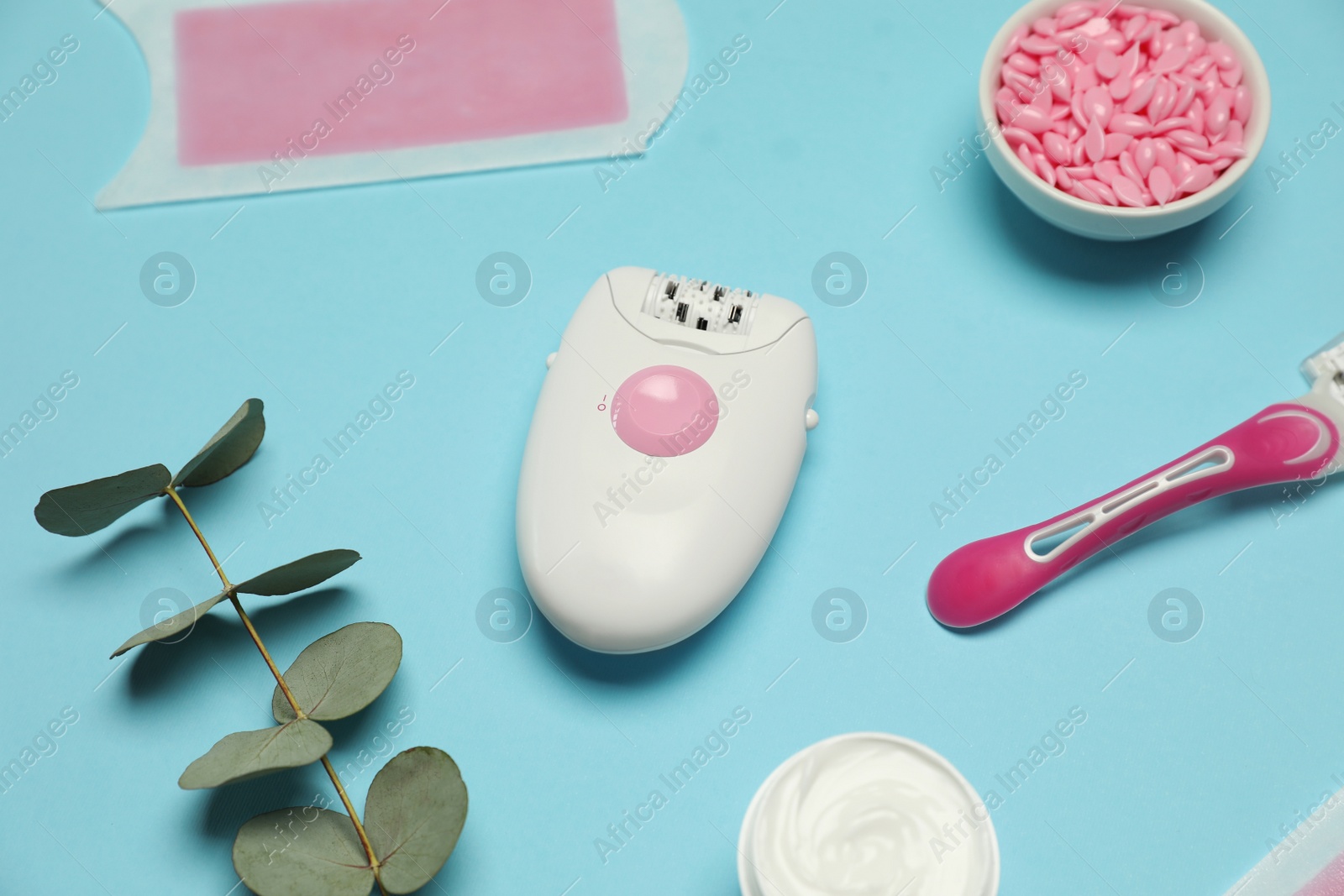 Photo of Epilator and other hair removal products on light blue background