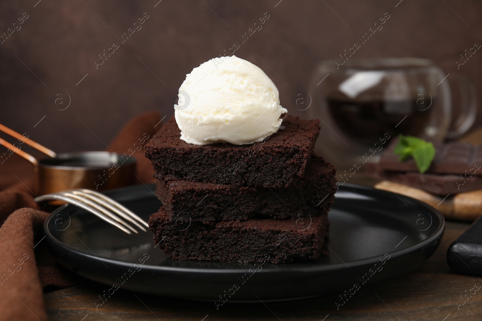 Photo of Tasty brownies served with ice cream on wooden table, closeup