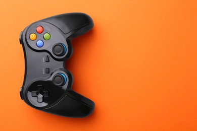 Photo of Wireless game controller on orange background, top view. Space for text