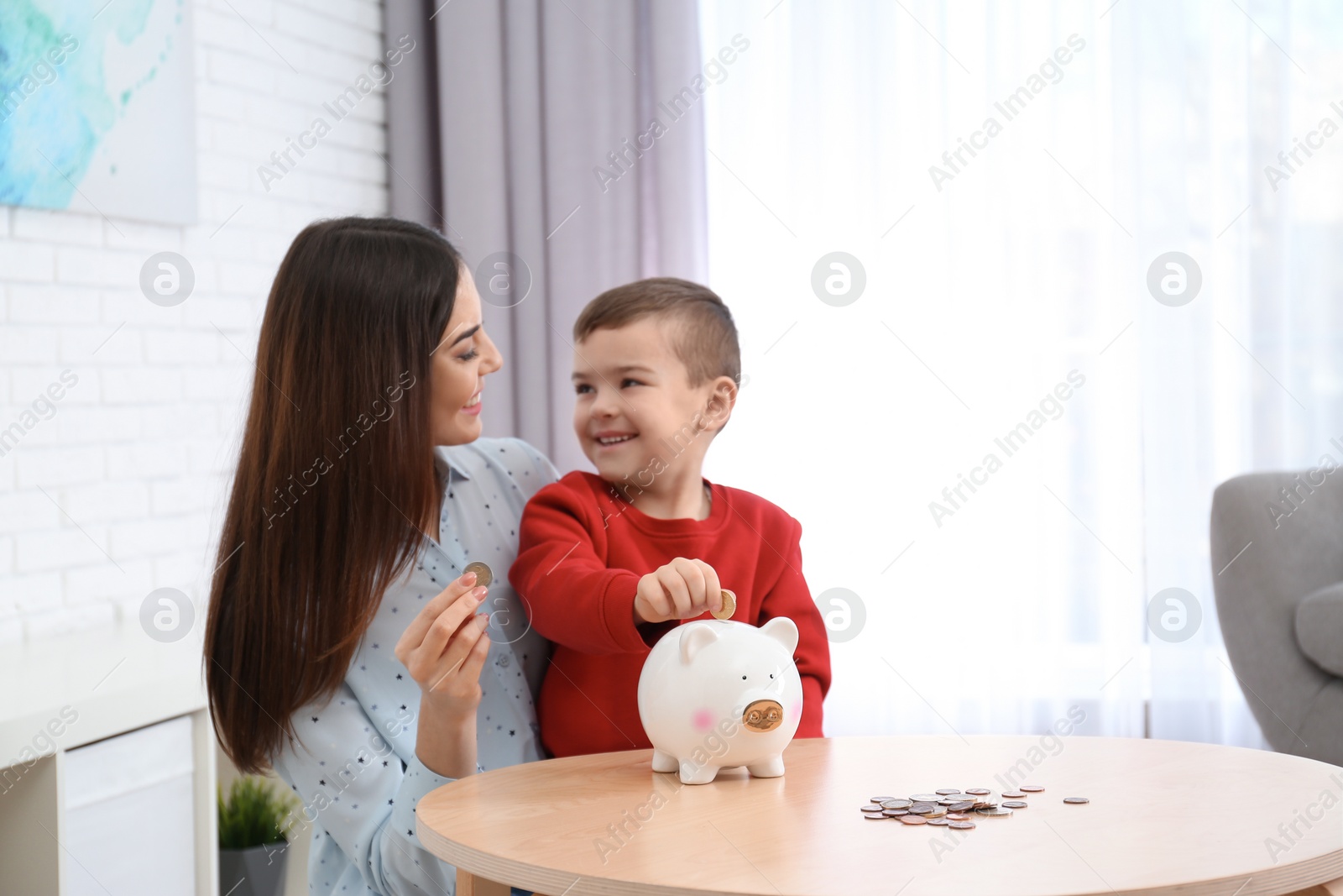 Photo of Happy mother and son with piggy bank and money at home