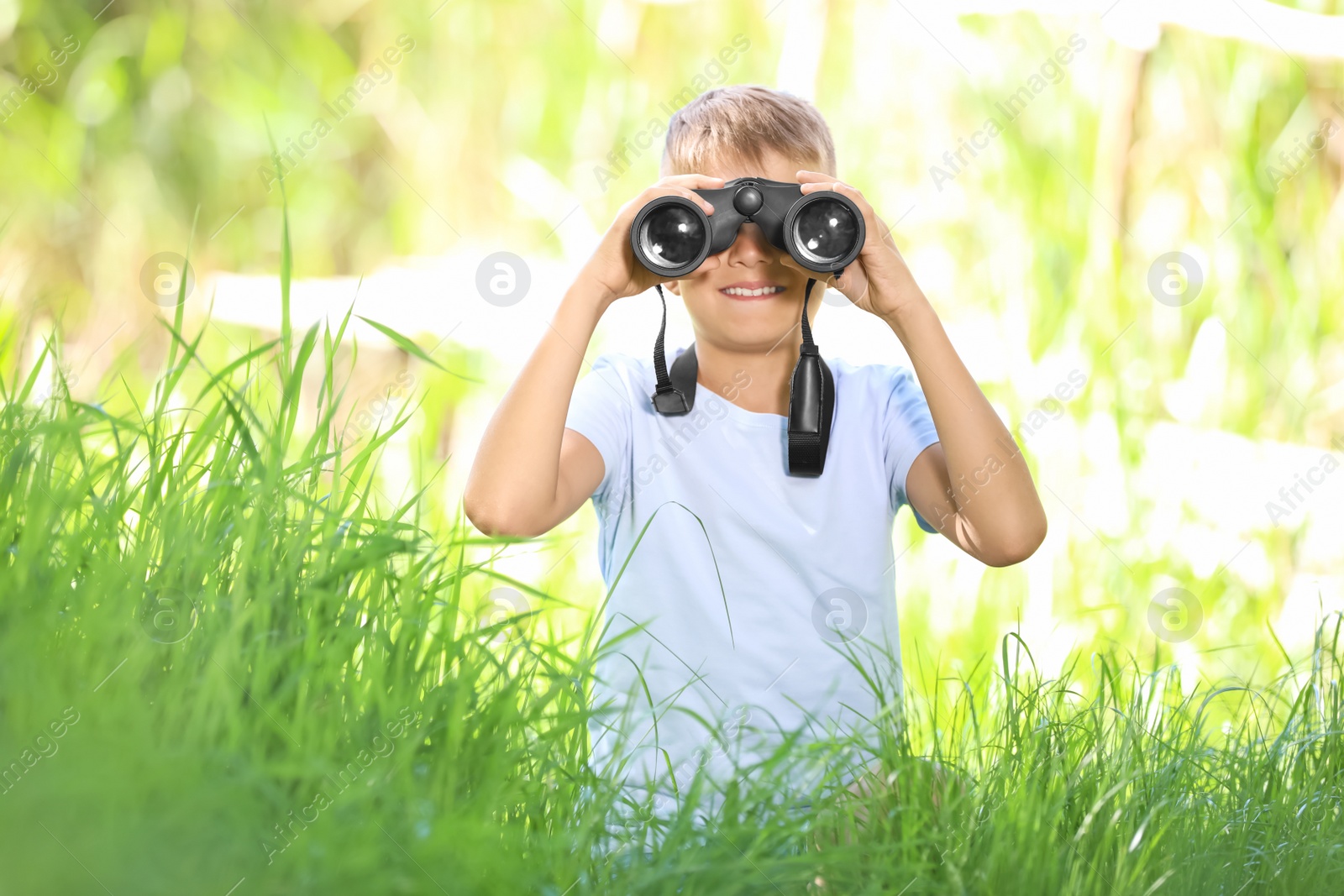 Photo of Little boy with binoculars outdoors. Summer camp